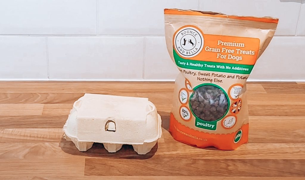 Egg Box Treats DIY Happiness Brain Game for Dogs Feature Photo: An image of a packet of Grain-Free Poultry treats sitting on the bench with an egg box carton.