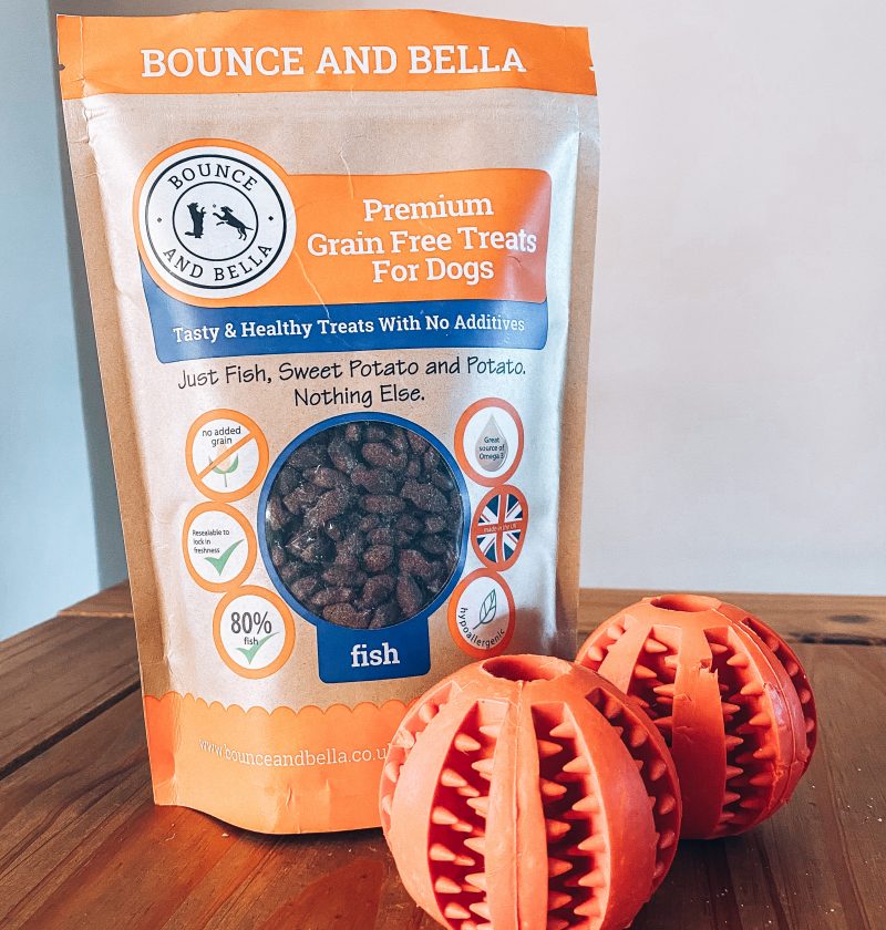 The Treat Ball Puzzle Game: A bag of grain-free poultry treats with two treat balls beside the packets.